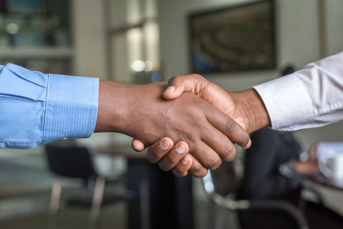 Two people shaking hands across a desk after closing a deal