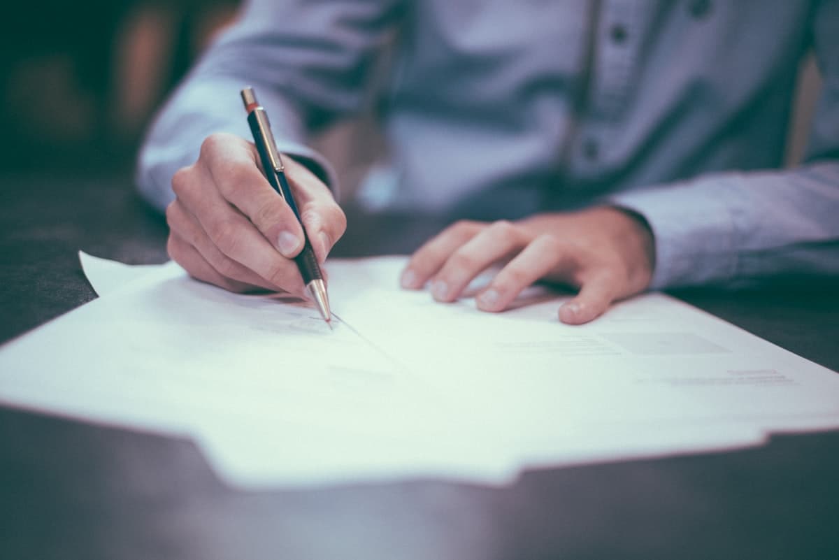 A person signing a property document at a desk